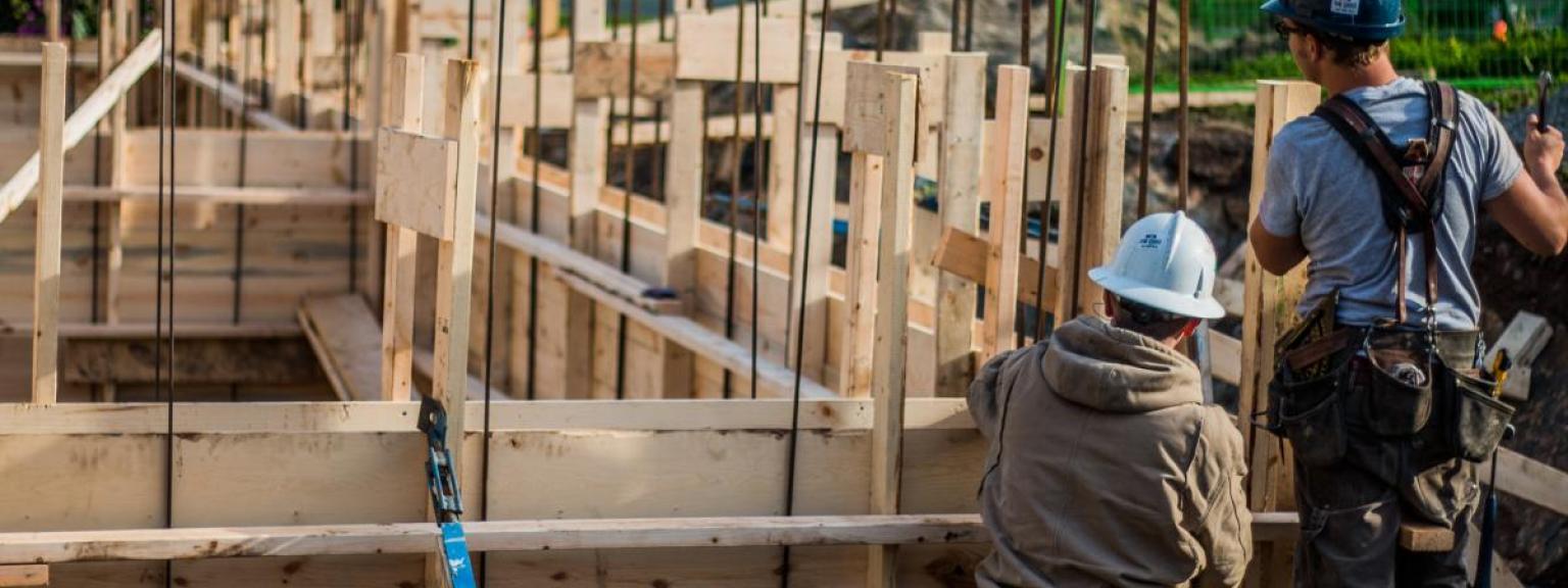 Construction workers building concrete framing for house foundation