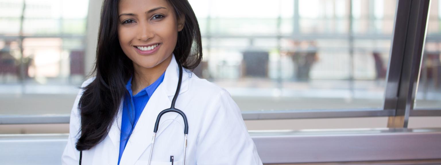 Closeup headshot portrait of friendly, cheerful, smiling confident female, healthcare professional with lab coat. isolated indoor clinic office background.