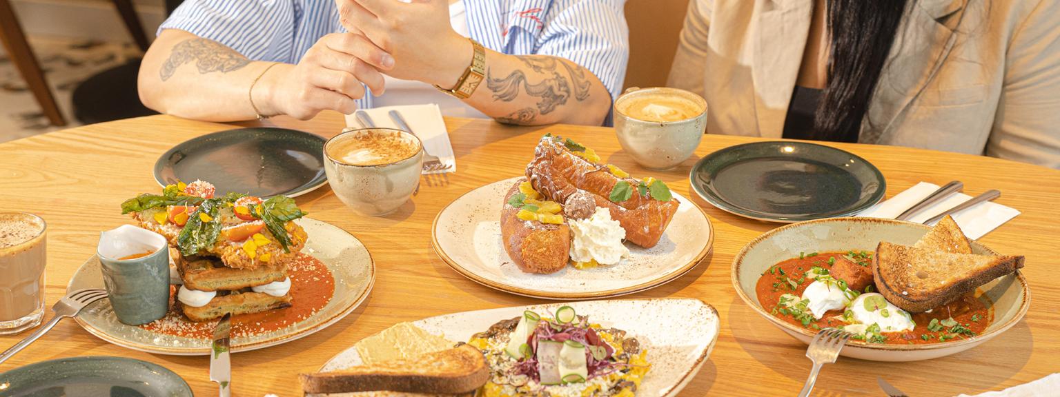 plates of food at a restaurant with two people in the background smiling