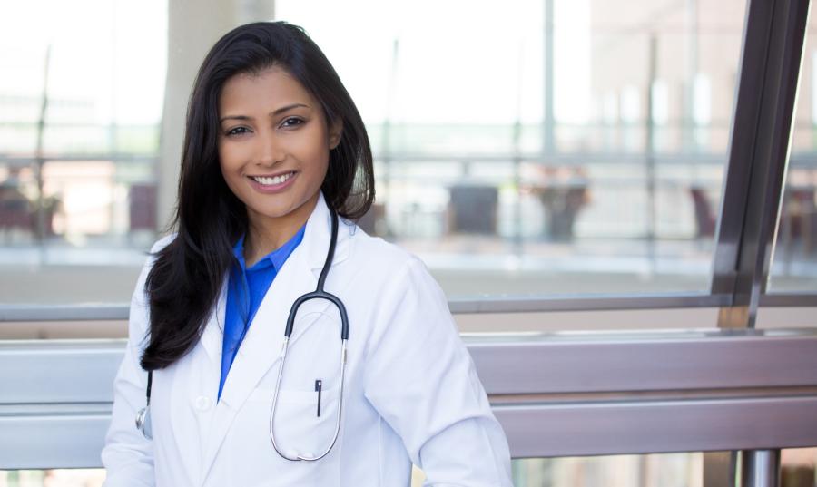 Closeup headshot portrait of friendly, cheerful, smiling confident female, healthcare professional with lab coat. isolated indoor clinic office background.