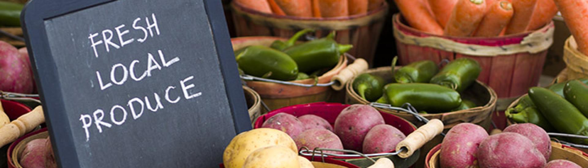 Produce on display with a sign stating "FRESH LOCAL PRODUCE"